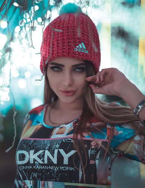 Women’s Clothing Brands Stylish woman wearing a red knit hat and graphic top, posing confidently.