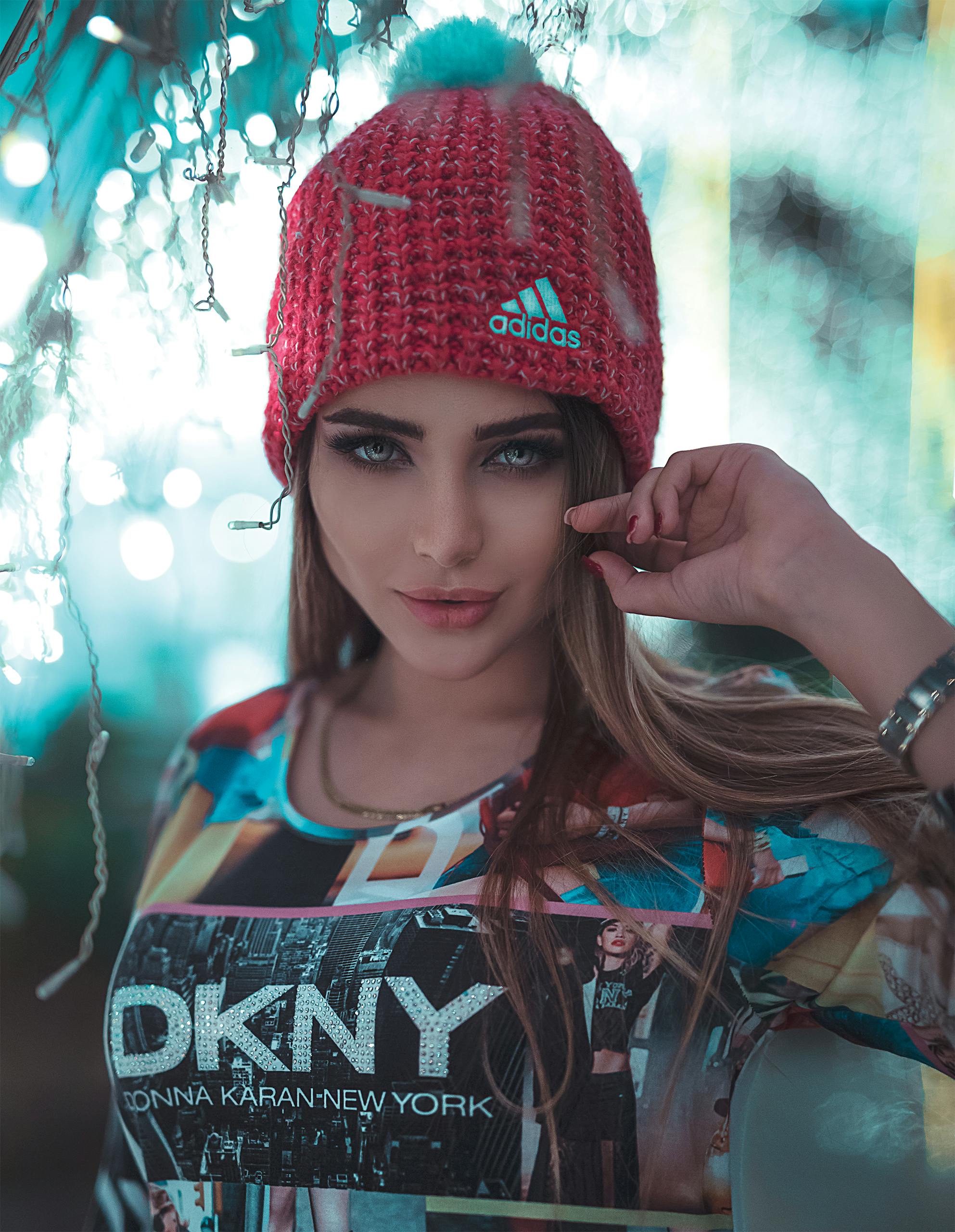Clothing Brands Women’s Clothing Brands Stylish woman wearing a red knit hat and graphic top, posing confidently.