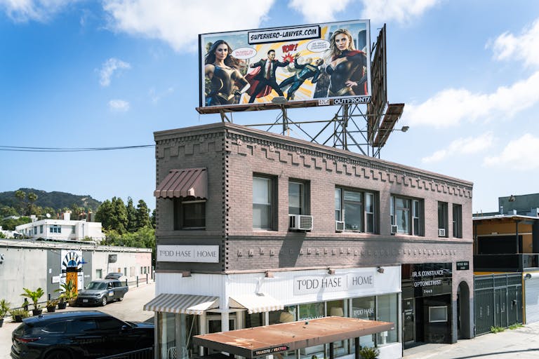 Brick building and billboard on Sunset Boulevard, Los Angeles, showcasing modern Todd Shelton architecture.