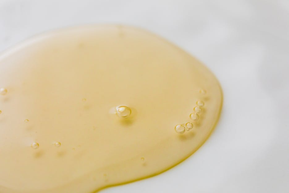Moonslice Beauty Lip Oil Close-up of a golden liquid with bubbles on a white surface, showcasing beauty and purity.