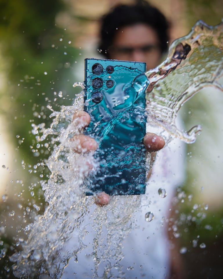 Samsung S25 Ultra Close-up of a smartphone enduring a splash of water, testing its durability.