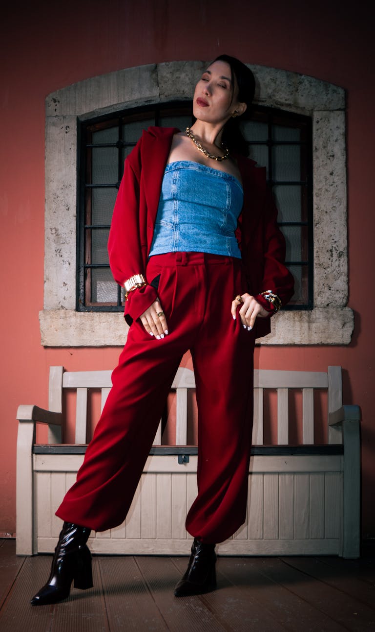 Fashionable woman Selvedge Denim in red suit and denim top posing indoors by a bench.