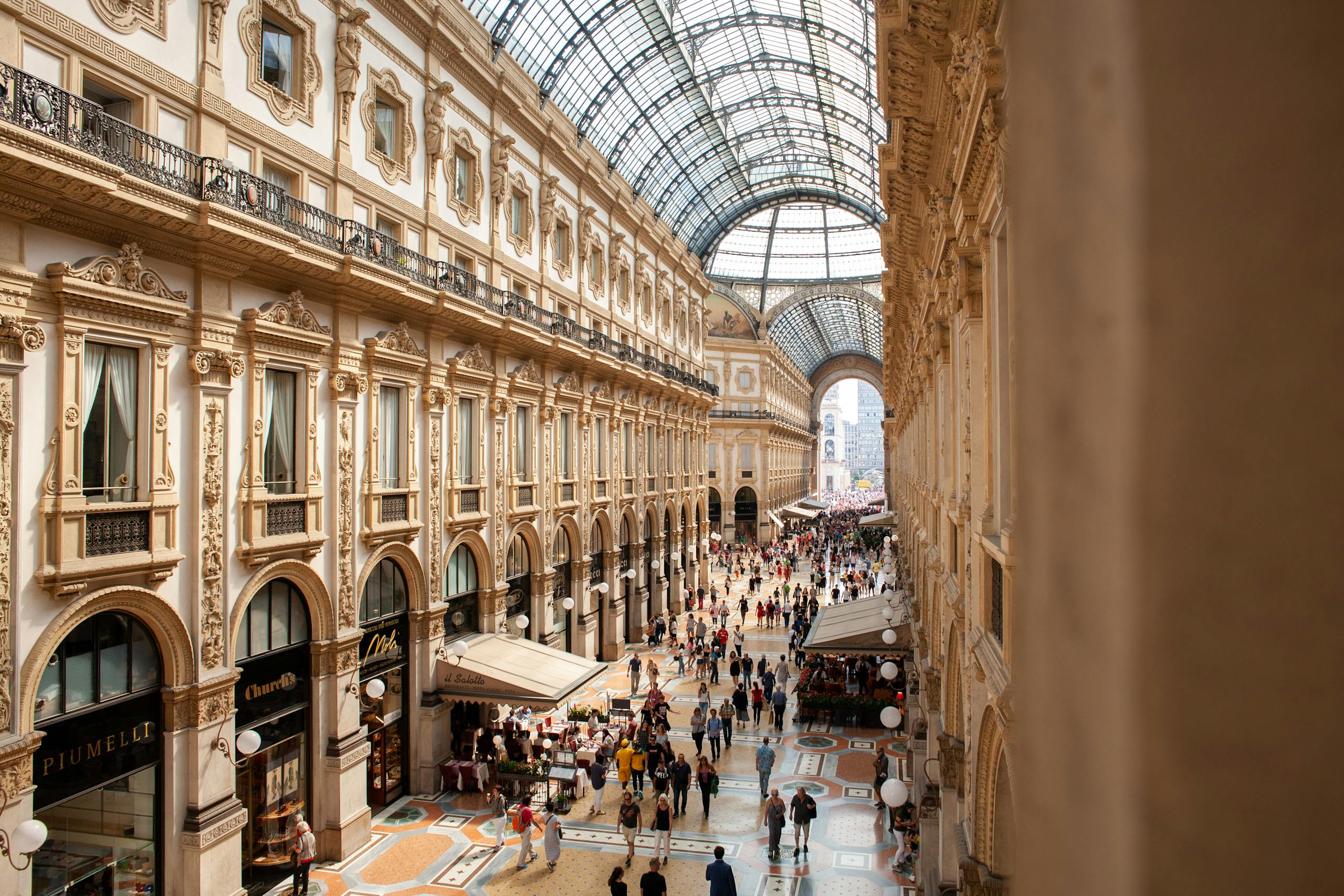 AC Milan vs SSC Bari Timeline Interior view of Galleria Vittorio Emanuele II in Milan, showcasing its stunning architecture and bustling crowds.