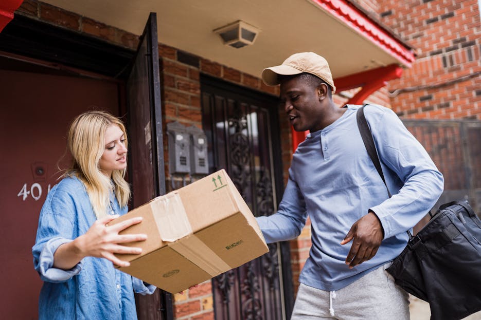 Magento Service Gonzay A delivery man handing a package to a woman at her doorstep, emphasizing delivery services.