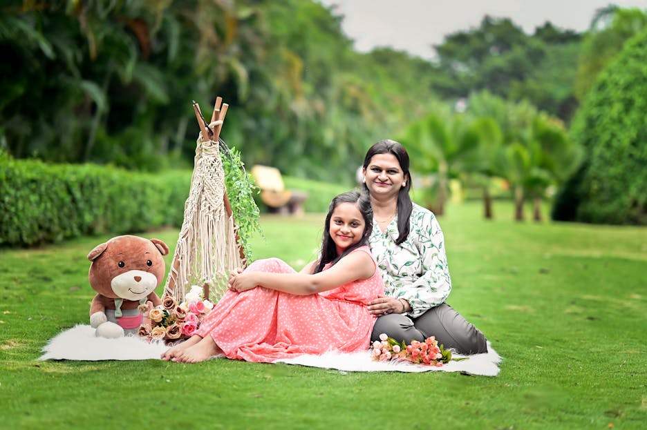 Bolly4u Me A joyful mother and daughter enjoy a picnic setting in a vibrant green garden.