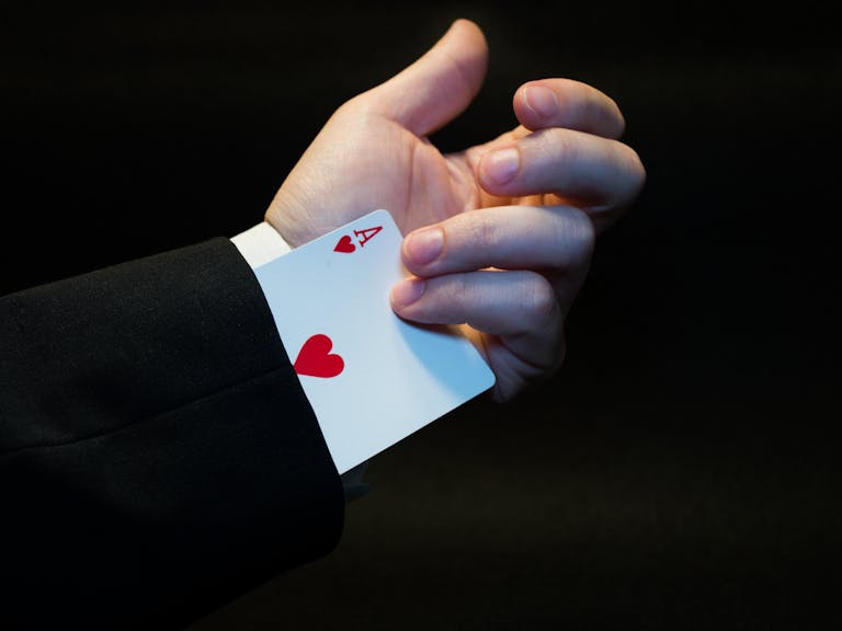 The Techno Tricks A magician's hand showing an ace of hearts hidden up the sleeve, symbolizing magic and trickery.