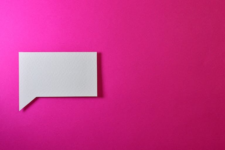 Xbocmy A minimalistic white paper speech bubble on a vibrant pink background, perfect for design projects.