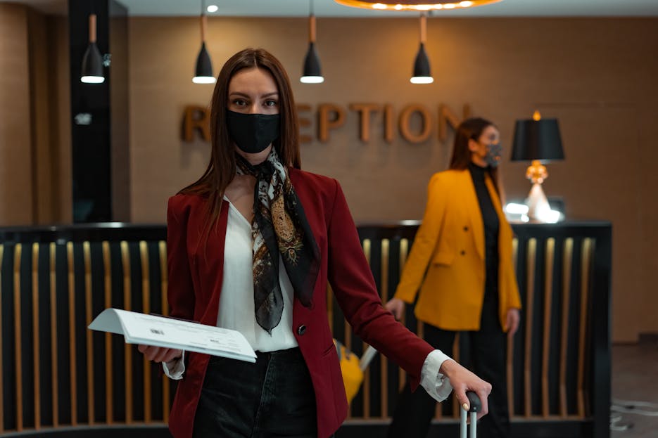 Check Whether 61479 Is Divisible  by 81 A woman in a mask stands at a hotel reception desk holding paper, welcoming service