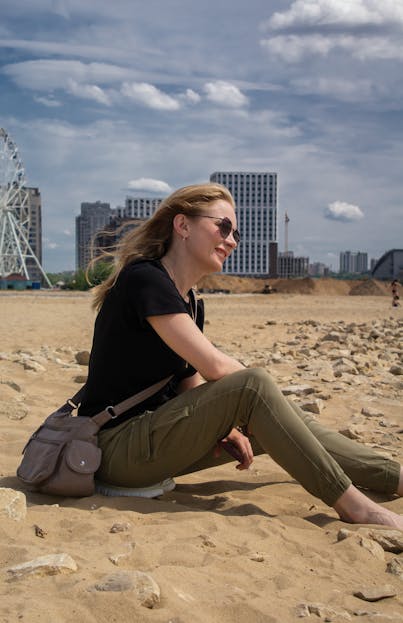 Russian Attack on Ukraine: A Defining Conflict Reshaping the World Order 2026 A woman in casual attire enjoys a sunny day on a sandy beach with a cityscape in the background, featuring a Ferris wheel.