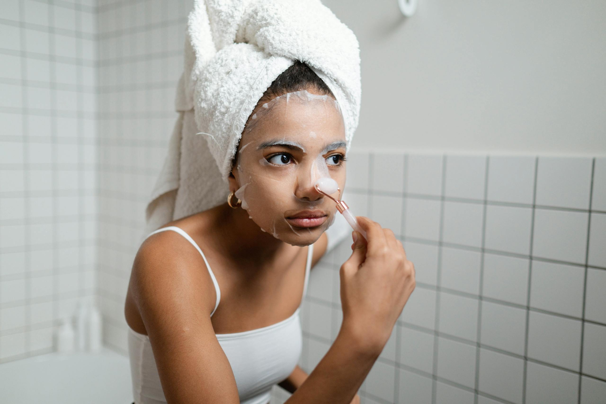 Well Health Tips in Hindi WellHealthOrganic A young woman applying a facial cosmetic mask in a modern bathroom, engaging in a beauty routine.