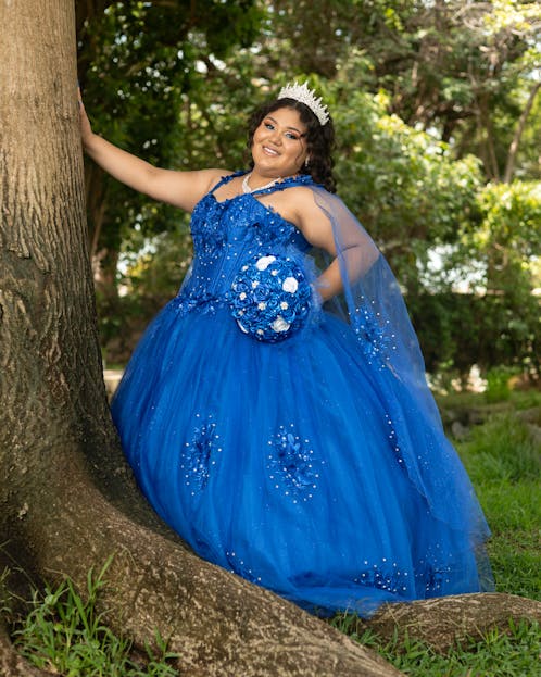 Veganov Trichy A young woman in a blue dress celebrating her Quinceañera outdoors in Mérida, Mexico.
