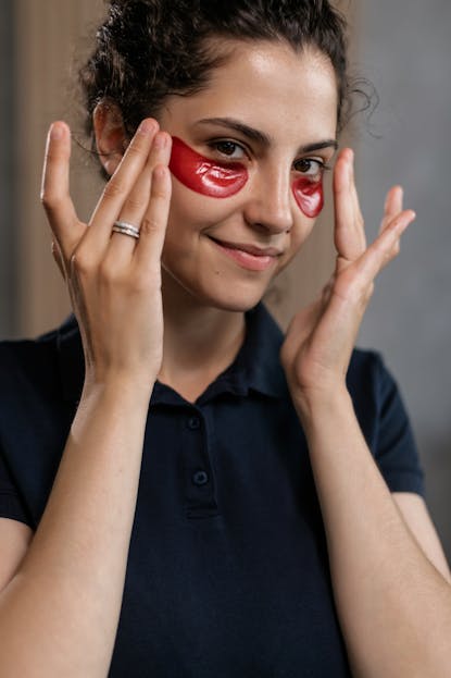 Woman applying under-eye masks indoors.