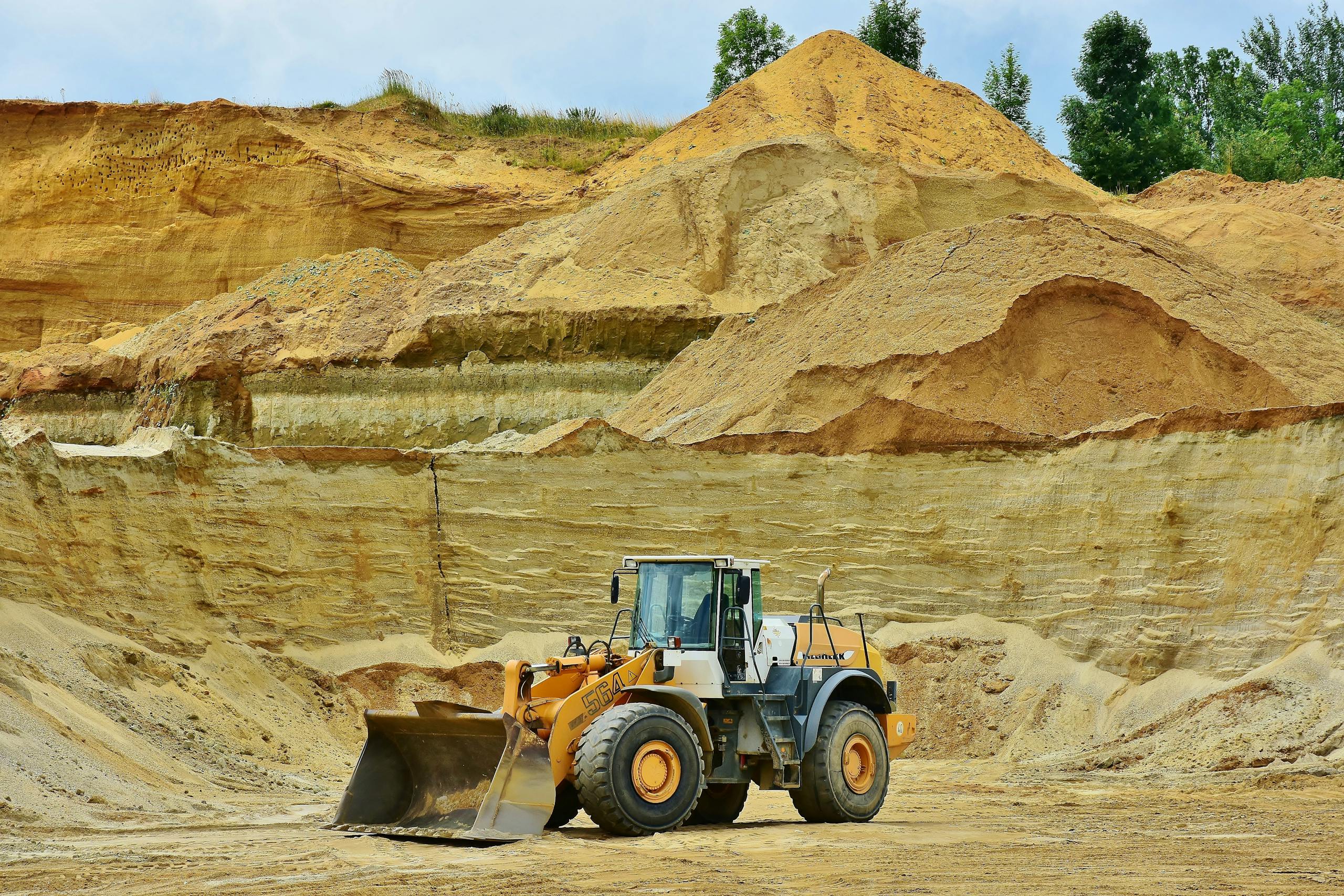 Buscrs An excavator working in an open pit mine surrounded by sandy terrain and clear sky.