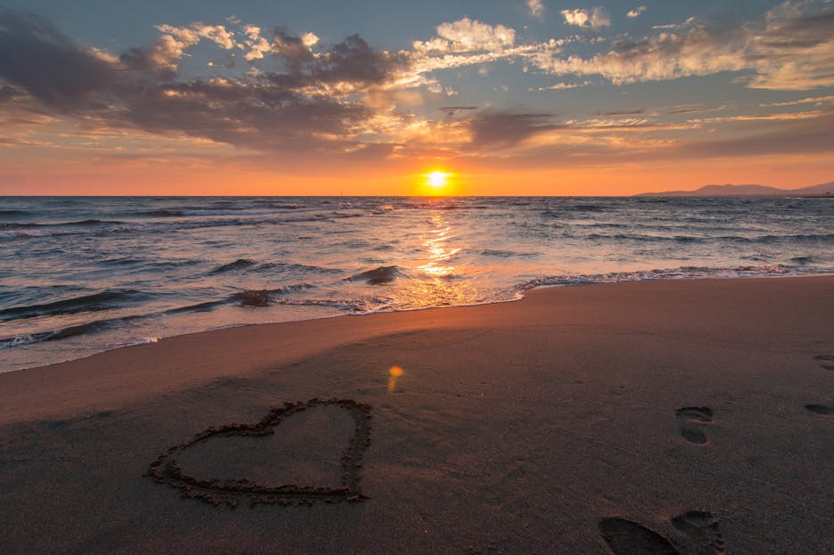 Sotwe Beautiful sunset over ocean with a heart shape in the sand, perfect for romantic themes.