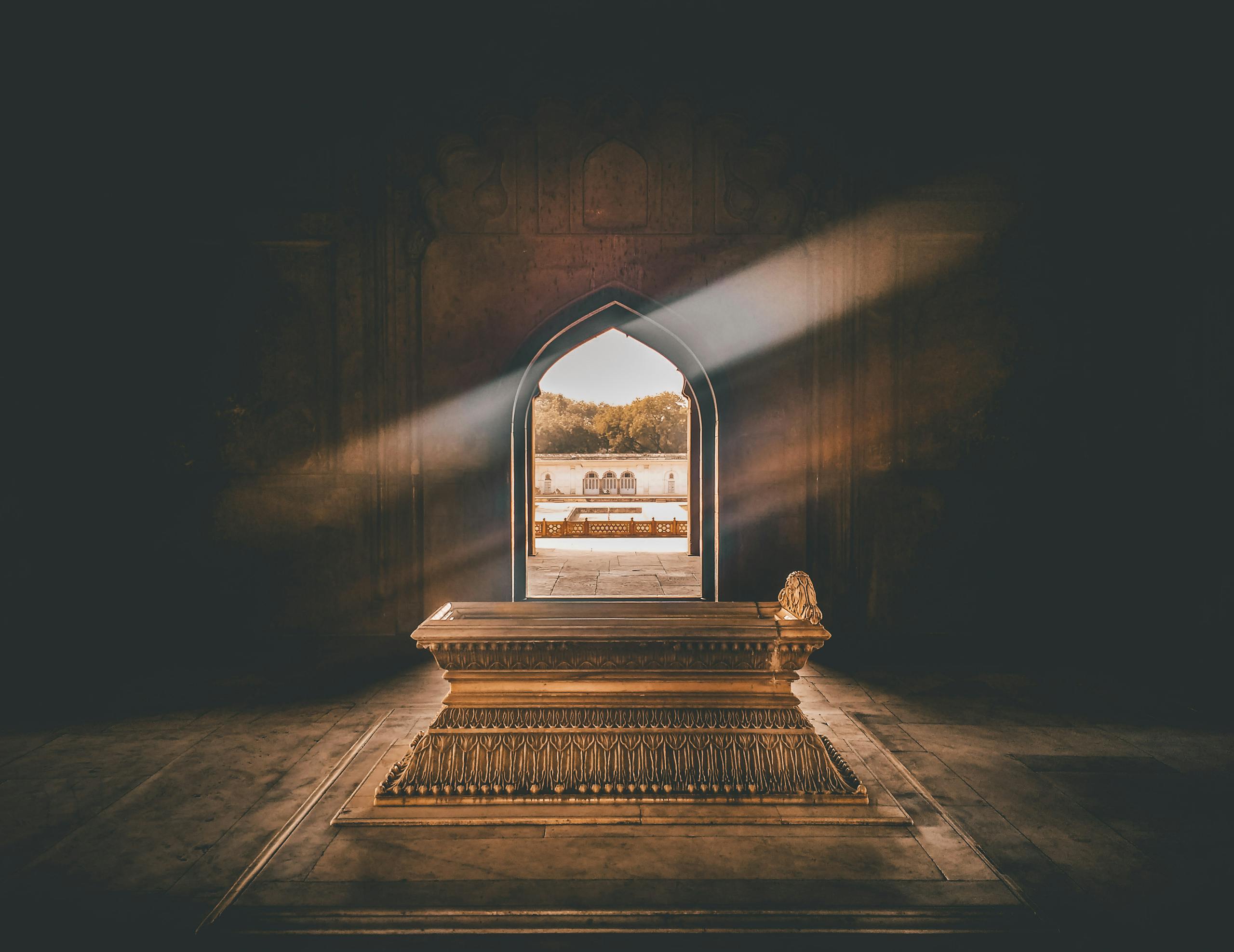 impupdates Beautiful tomb interior with a golden sarcophagus, illuminated by sunlight through an ornate archway.