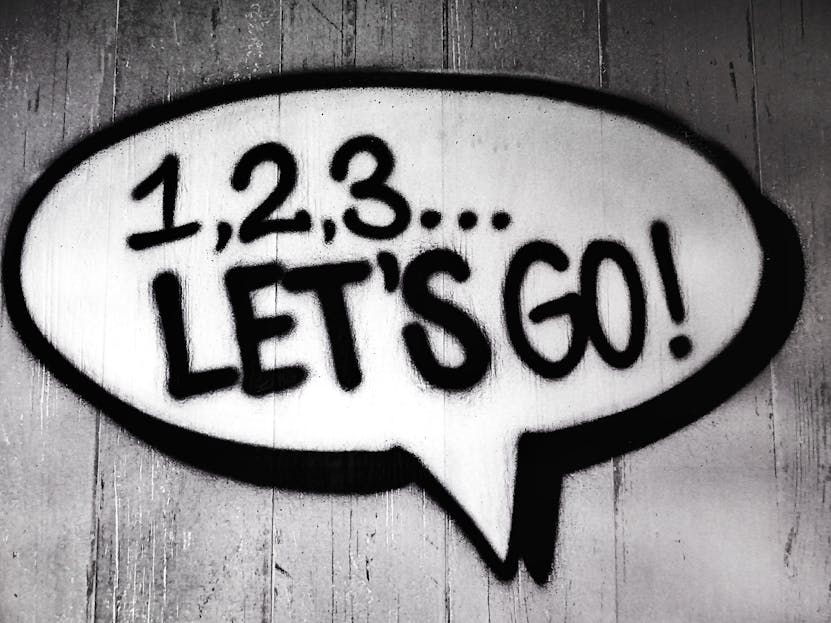 DainikShiksha.com Black and white street art featuring a bold motivational message in a speech bubble.
