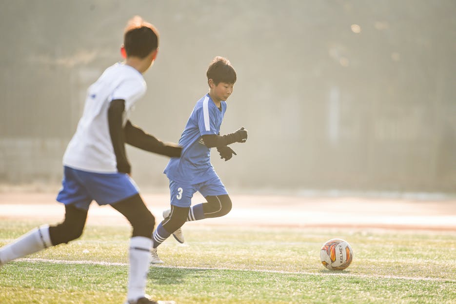Runlia Boys playing soccer on a sunny day, capturing focus and movement on sports field.