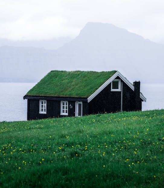Onnilaina Charming black wooden house with a grass roof in the tranquil Faroe Islands landscape.