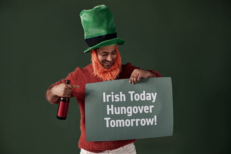 Latest News Today Happy man dressed as a leprechaun holding a themed sign and drink.