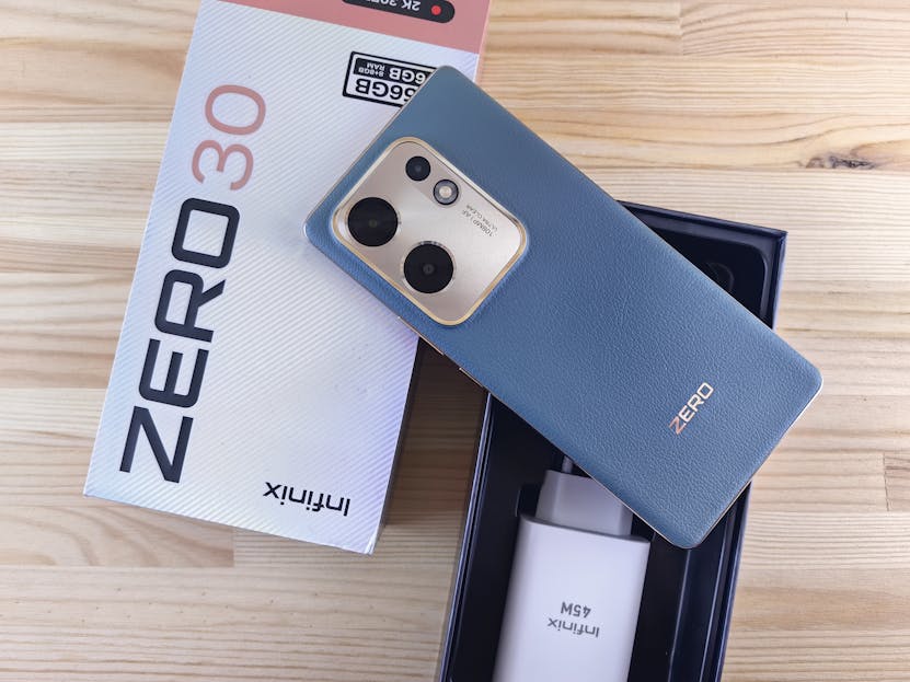 Latest News Today Latest News Today Infinix Zero 30 smartphone with original packaging and accessories on a wooden surface.
