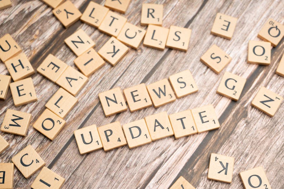 Latest News Today Scrabble tiles spelling 'News Update' on a wooden background, ideal for media and communication concepts.