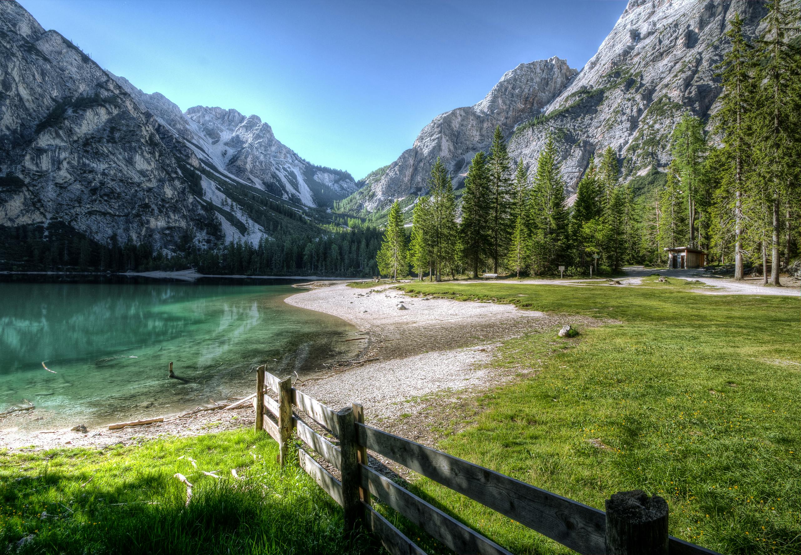 Cartetach Serene mountain lake with green trees and a rustic fence, perfect nature backdrop.