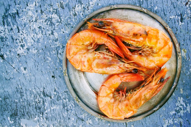 Gastroshiza Top view of cooked shrimps on a metal plate on rustic surface. Perfect for seafood lovers.