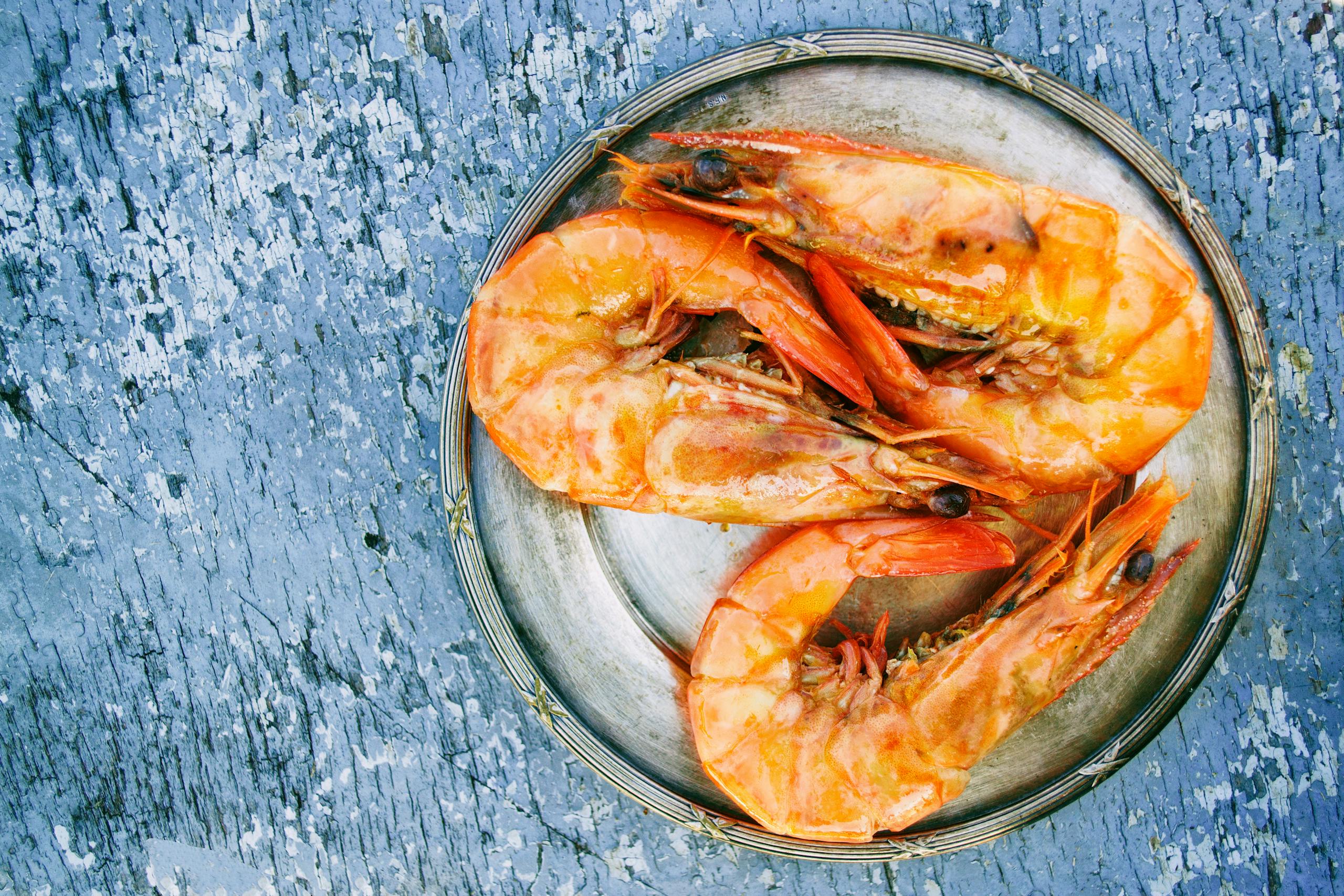 Gastroshiza Top view of cooked shrimps on a metal plate on rustic surface. Perfect for seafood lovers.
