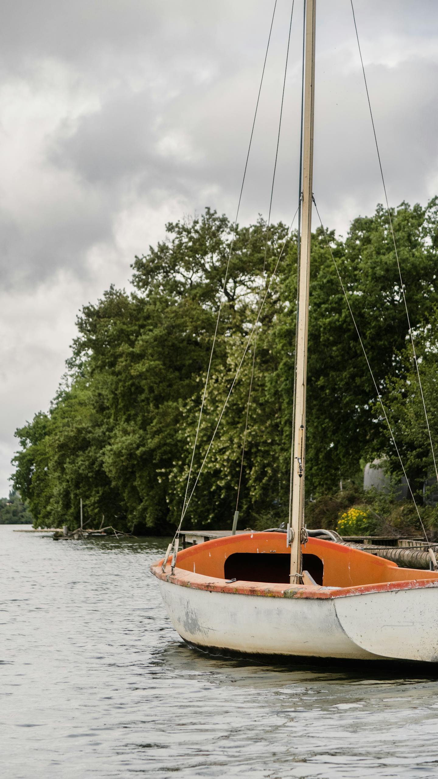 Calmered Tranquil scene of a sailboat on a river in Carbonne, Occitanie, France, surrounded by lush greenery.