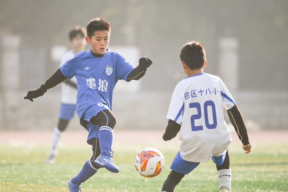 Runlia Two young soccer players in action on the field under sunlight. Captured dynamic sports moment.