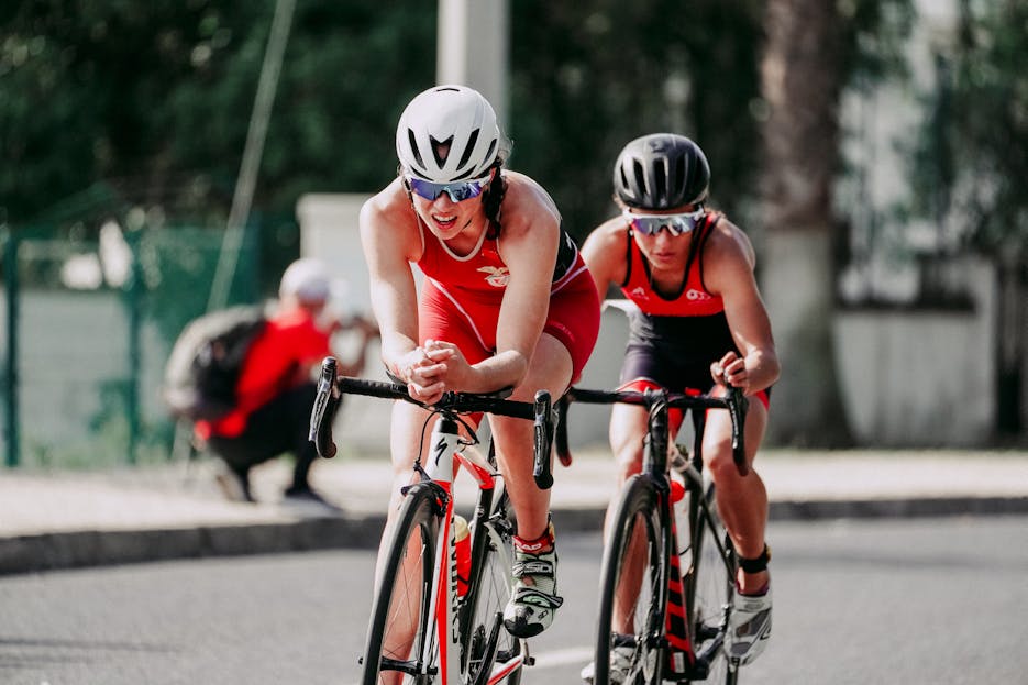 Vitilinox Unrecognizable cyclists riding bikes with hands on handlebars while taking part in bicycle race in daytime on blurred background