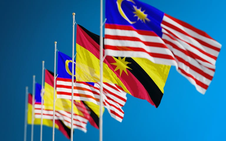 Asian Pinay Vibrant display of Malaysian and Sarawak flags symbolizing unity and patriotism against a clear blue sky.