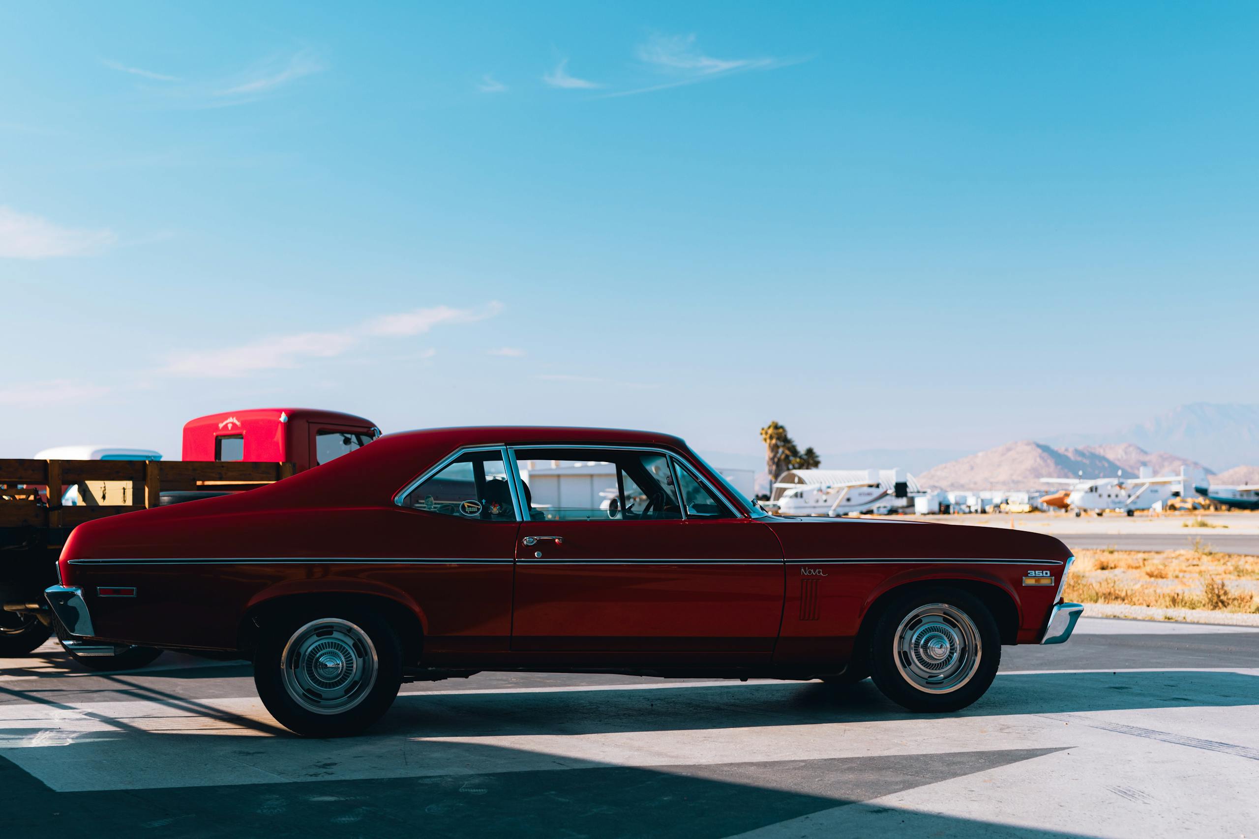 Nova Scola Vintage Chevrolet Nova under a clear blue sky in a sunny parking lot.