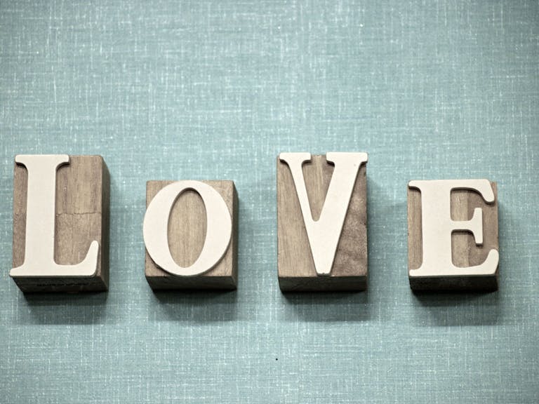 Fontlu Wooden block letters spelling 'love' on a textured blue background, ideal for creative projects.