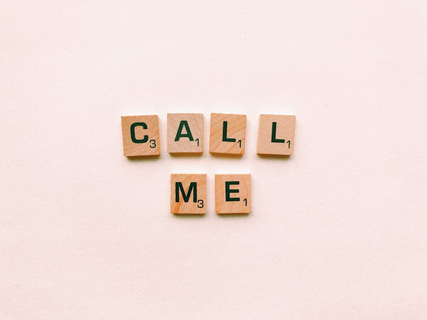 Bolly4u Me Wooden letter tiles spelling 'Call Me' on a pastel pink background, invoking communication and connection.