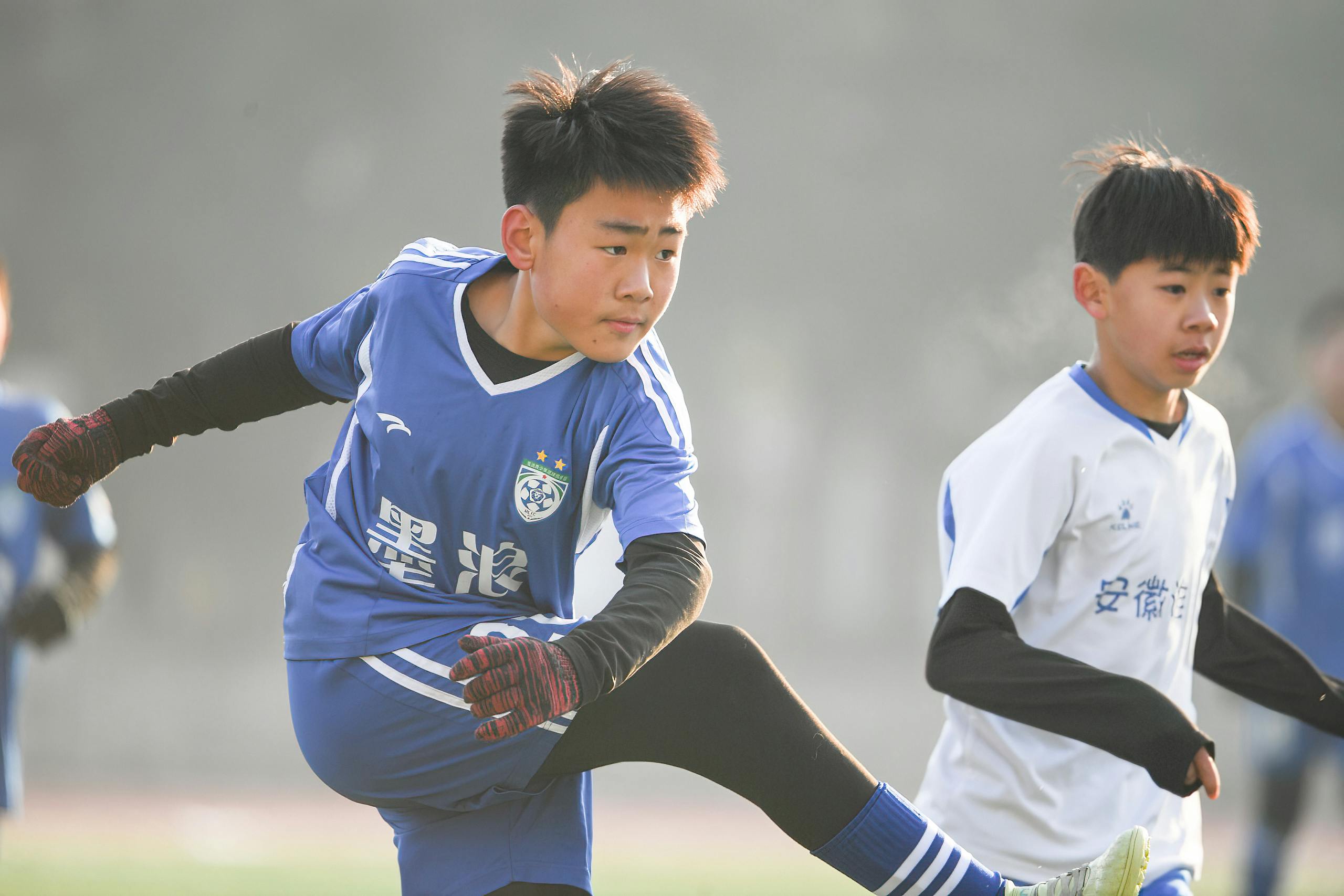Runlia Young athletes playing soccer on a foggy day, showing skill and determination.