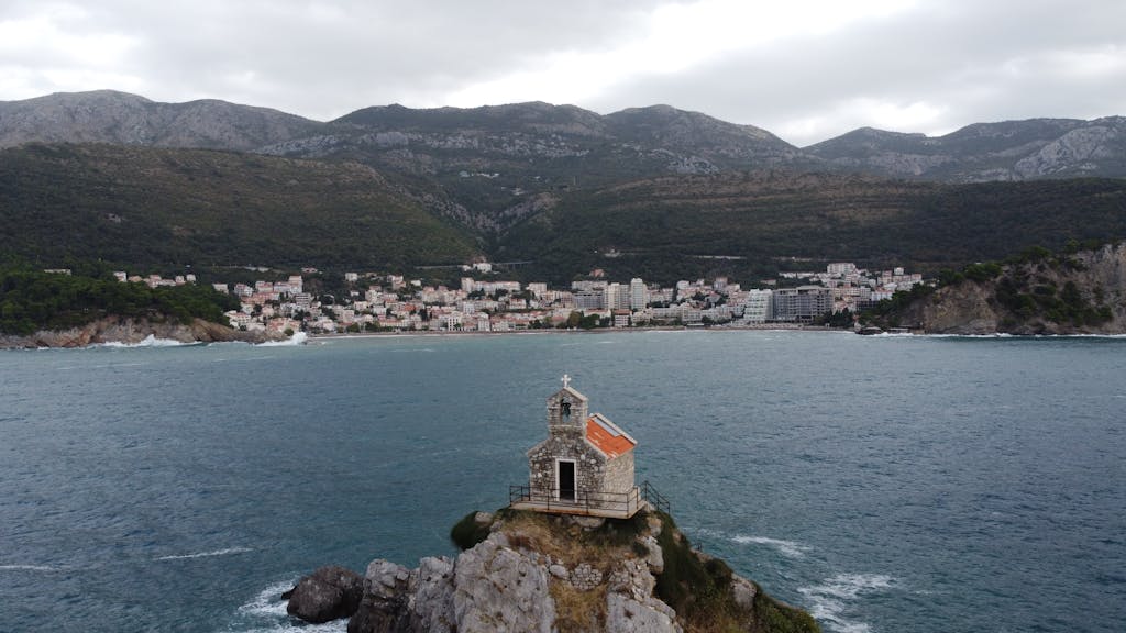 aajkitajikhabar .com A breathtaking drone shot over Petrovac, showcasing a historic church on the Adriatic coast.