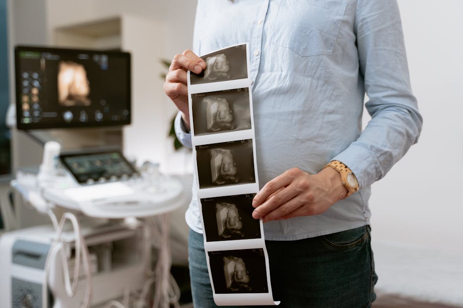 Kongotech Org A person holding ultrasound images in a medical clinic, showcasing pregnancy monitoring.