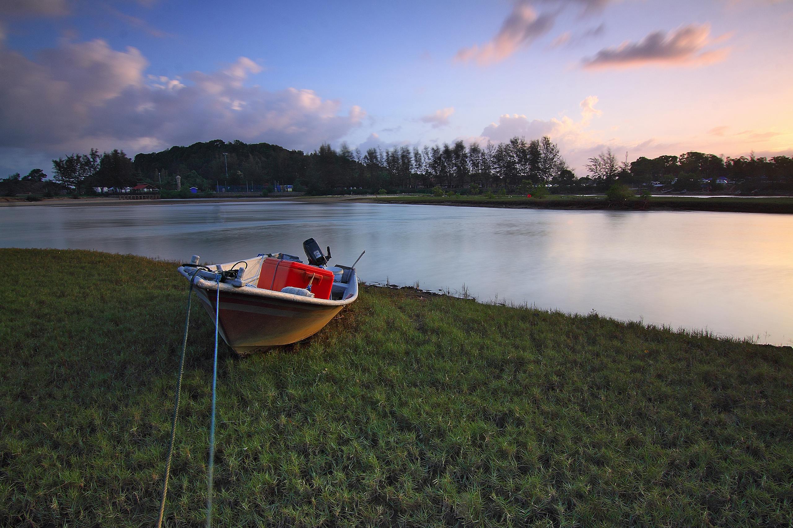 Miami Dolphins A serene scene of a boat by a riverbank at sunset, surrounded by nature.