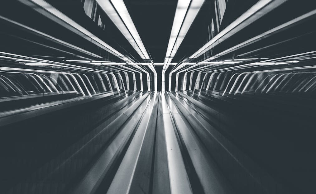 whatsontech Abstract black and white image capturing futuristic light streaks in a modern tunnel, creating a dynamic sense of motion.