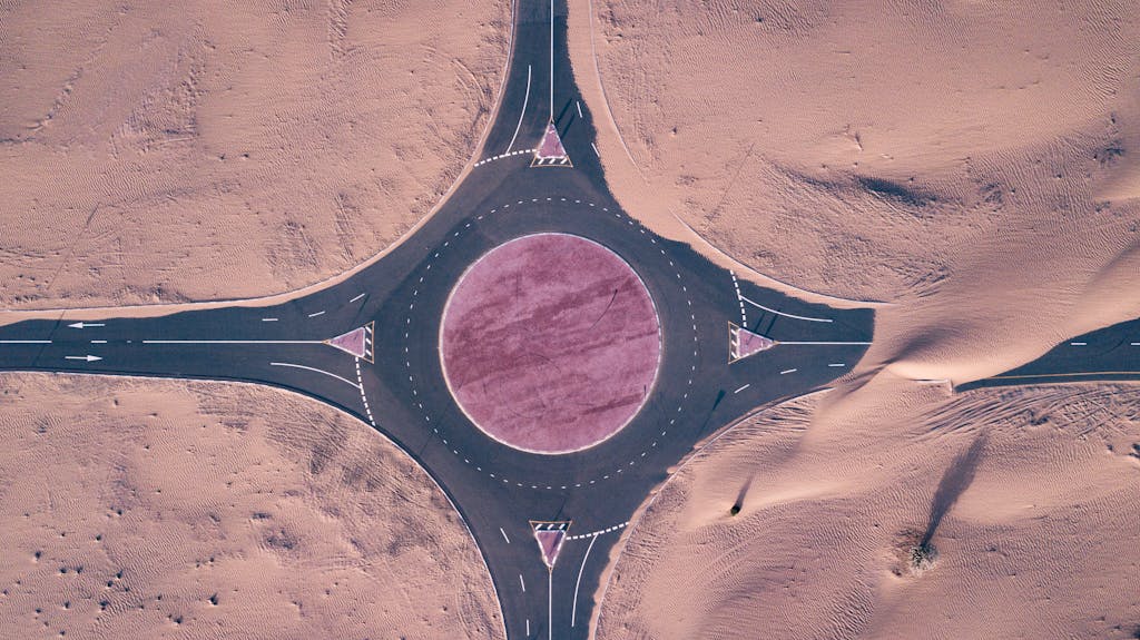 realize infrastructure navigator  Aerial view of a stark roundabout surrounded by endless desert sand dunes.