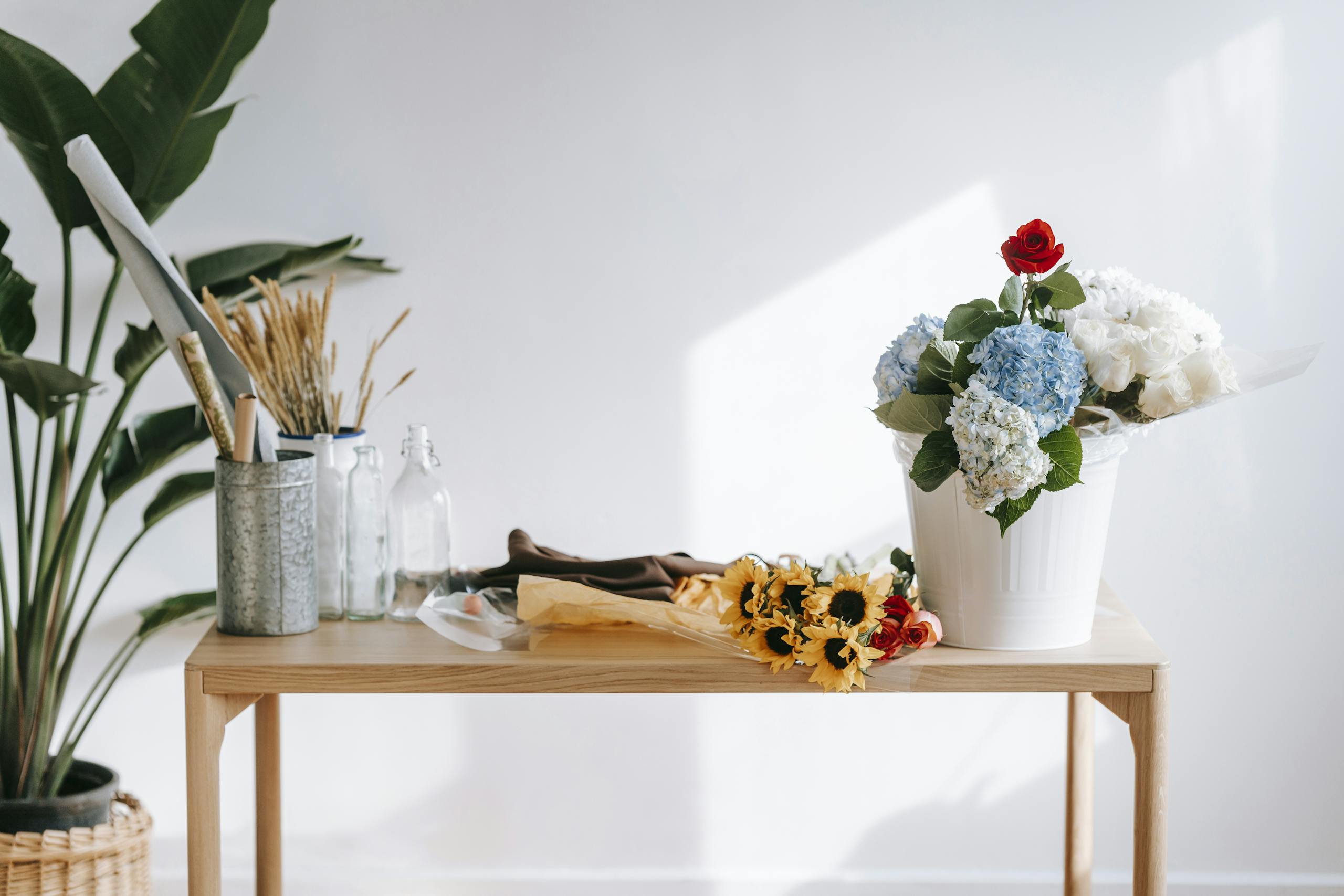 Shop Spring Vase Beautiful bouquet of roses and hydrangeas on a wooden table in a bright, modern space.