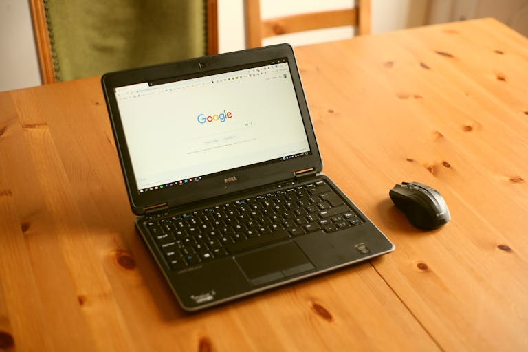 Best API Search Company’s Homepage Black laptop and mouse on a wooden desk with Google homepage open.