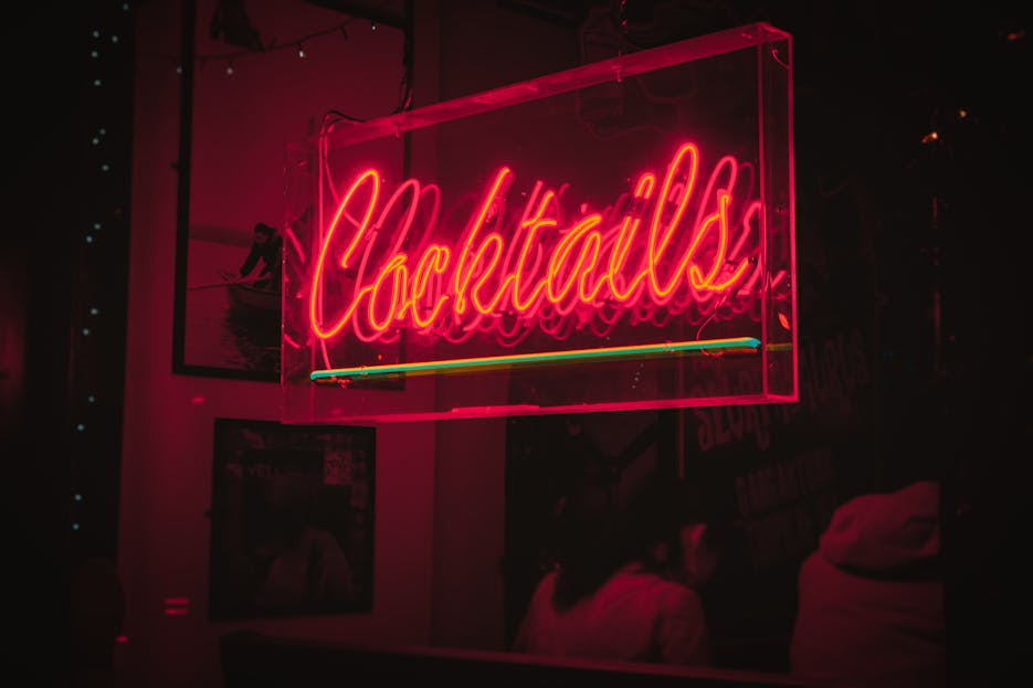 Crackstube Bright neon 'Cocktails' sign glowing in a lively Dublin bar at night.