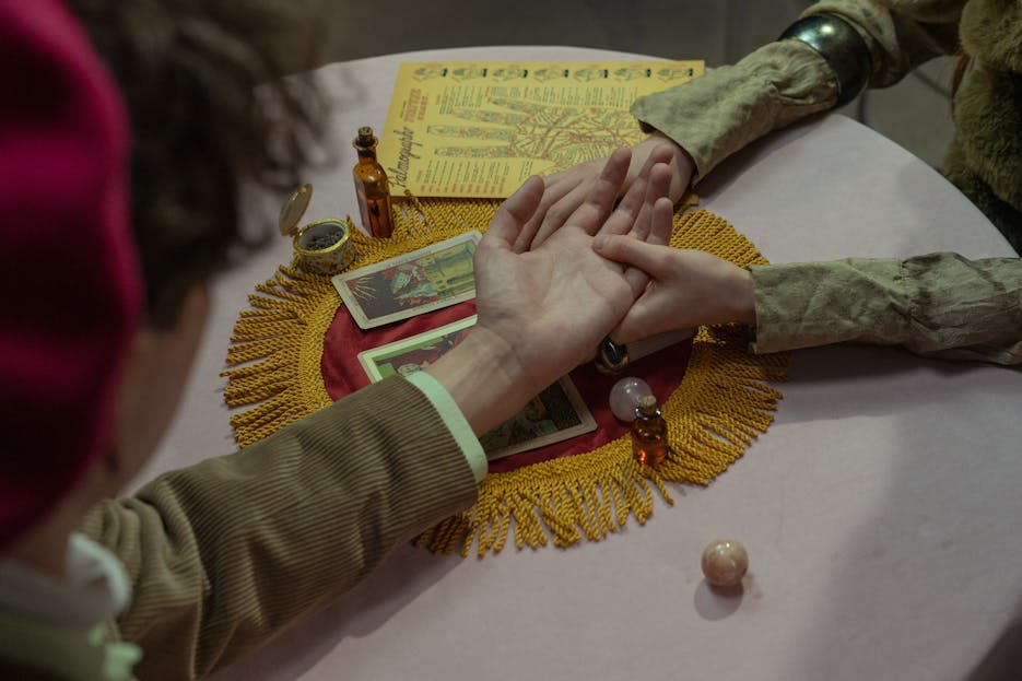 Nueraji vs Crosbie Prediction Close-up of a fortune-teller performing a palm reading wi
th tarot cards on a decorated table.