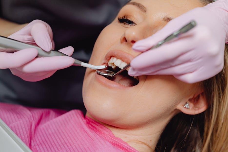 Dental Software News Today Close-up of a woman receiving dental care with a dentist using tools inside a clinic.
