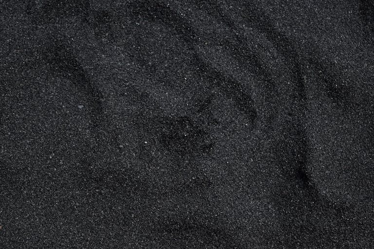 ChatPic Close-up of black sand texture from Waimea Beach in Hawaii. Ideal for backgrounds.