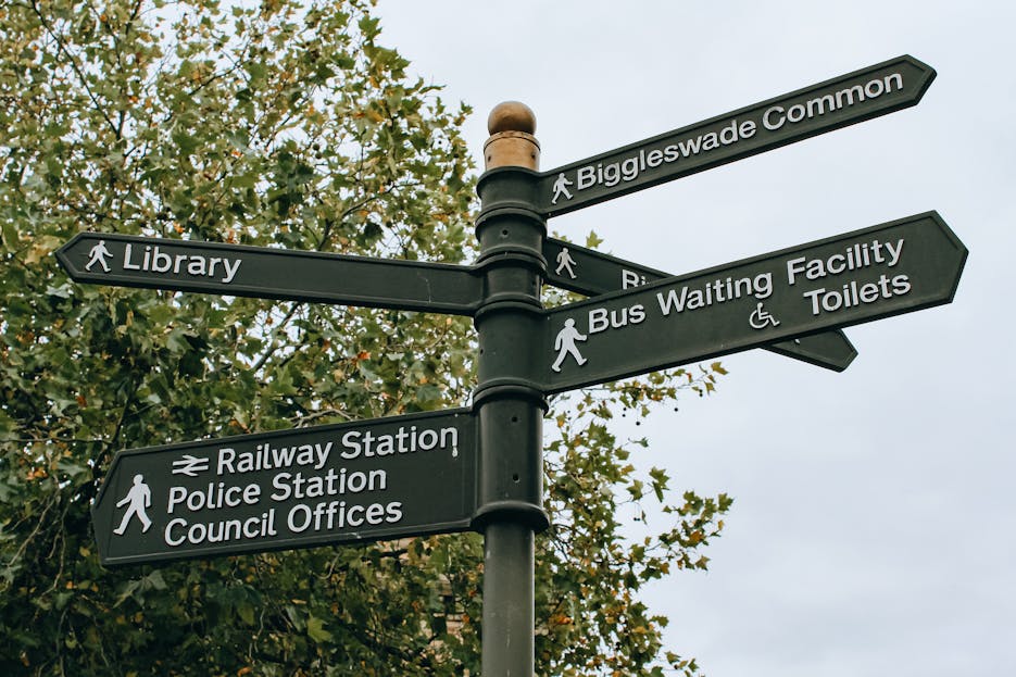 630 Area CodeFrom below poled signpost placed near lush green tree and showing direction to city facilities in daylight