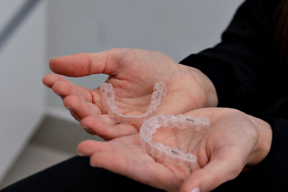 Trios 5 Invisalign Submission Hands holding clear dental aligners in a modern dental office in Belo Horizonte.