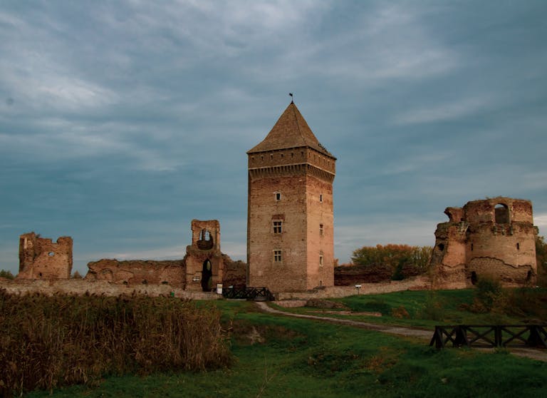 bac stock Historic medieval tower and ruins in Bač, Serbia, captured under a cloudy sky.